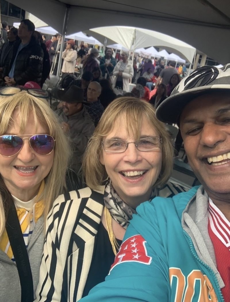 Three people smiling at an outdoor community event